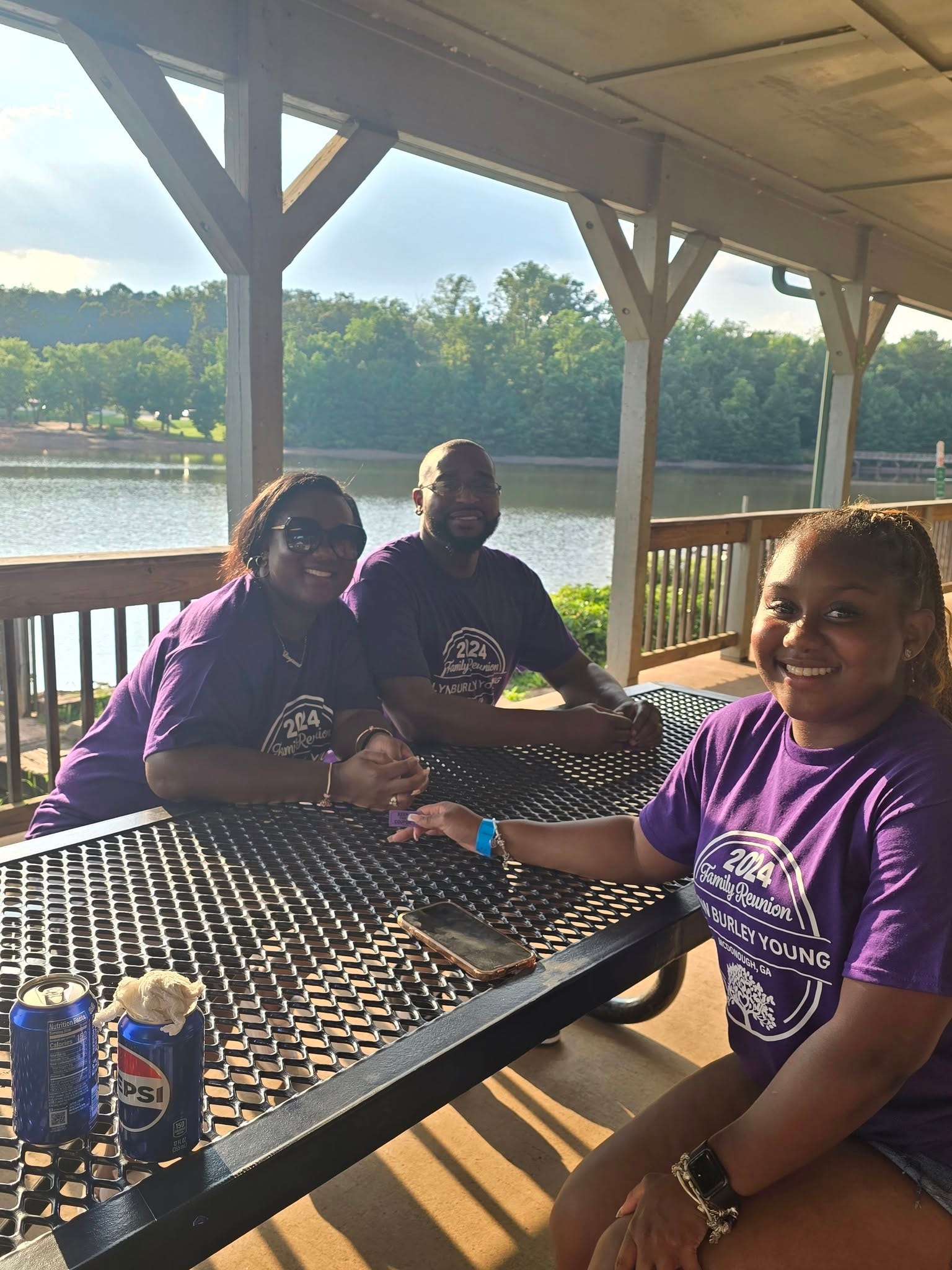 Three family members at lakeside pavilion in reunion shirts