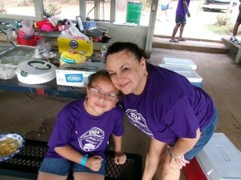 Family group of five in purple reunion shirts at pavilion picnic table